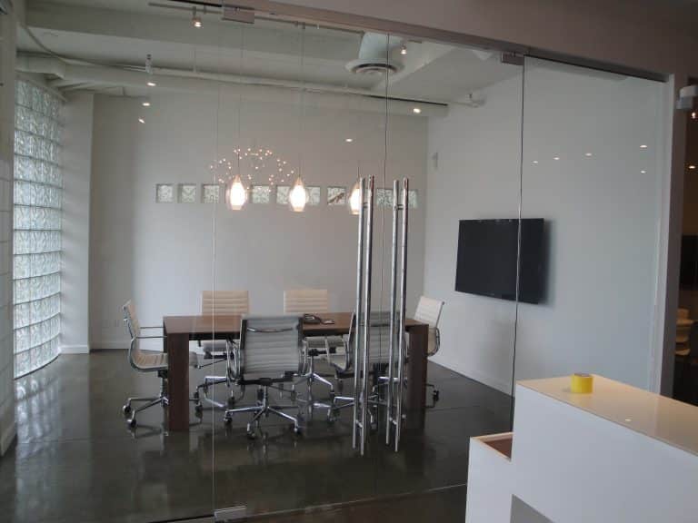 A modern glass partition office with a sleek table and chairs